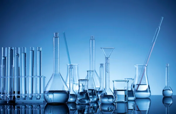 Laboratuvar araştırmaları. Mavi arka planda cam tüpler ve beherler.