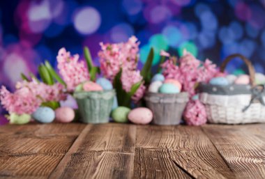 Paskalya geçmişi. Paskalya yumurtaları ve bahar çiçekleri. Kırsal ahşap masa. Pastel renkler bokeh. Tipografi için yer.