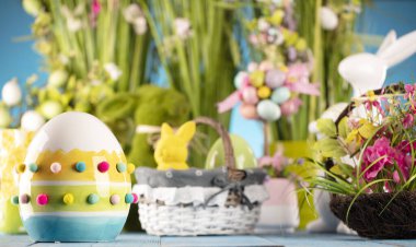 Paskalya teması. Paskalya süsleri. Sepet içinde paskalya yumurtaları ve lahana yaprağı. Bahar çiçeği buketi. Mavi arkaplan.