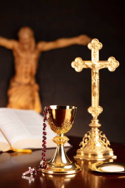 Dini bayram Paskalyası. Katolik sembolleri kompozisyonu. İsa figürü, Haç, Monstrance, Kutsal İncil, gri arka planda tespih ve altın kadeh.. 