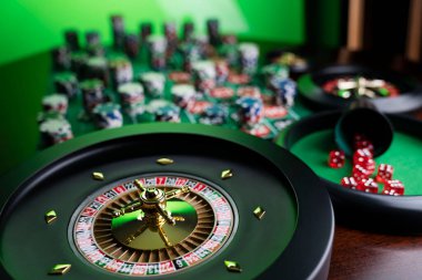 Kumarhane. Kumar oyunları teması. Kumarhanedeki rulet çarkı, zar ve poker fişleri yeşil masa gibiydi..