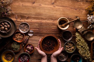 Doğal tıp geçmişi. Bitki kompozisyonu hazırlama. Kâselerde çeşitli kuru otlar ve rustik ahşap masa üzerinde pirinç havan..