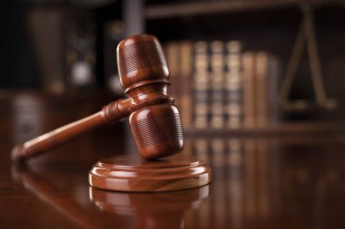 Hukuk teması. Avukatlık bürosu. Gavel ve tartıyı kahverengi masaya koy. Yasal kitaplarla dolu bir kitaplık..