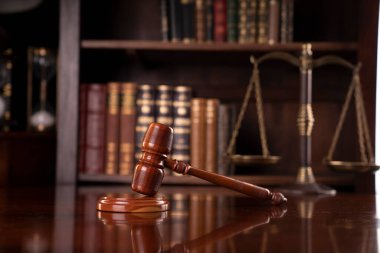 Hukuk teması. Avukatlık bürosu. Gavel ve tartıyı kahverengi masaya koy. Yasal kitaplarla dolu bir kitaplık..