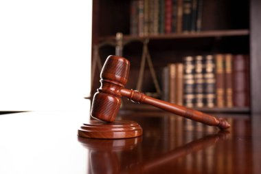 Hukuk teması. Avukatlık bürosu. Gavel ve tartıyı kahverengi masaya koy. Yasal kitaplarla dolu bir kitaplık..