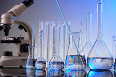 Coronavirus salgını teması. Hızlı covid testleri ve anti-covid aşısıyla ilgili bilimsel araştırma. Mavi arka planda mikroskop, deney tüpleri ve deney tüpleri..