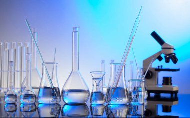 Coronavirus salgını teması. Hızlı covid testleri ve anti-covid aşısıyla ilgili bilimsel araştırma. Mavi arka planda mikroskop, deney tüpleri ve deney tüpleri..