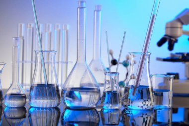 Coronavirus salgını teması. Hızlı covid testleri ve anti-covid aşısıyla ilgili bilimsel araştırma. Mavi arka planda mikroskop, deney tüpleri ve deney tüpleri..