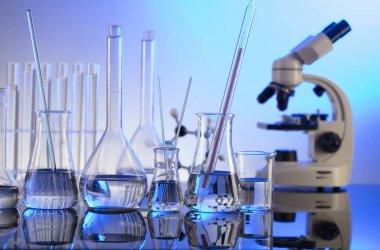 Coronavirus salgını teması. Hızlı covid testleri ve anti-covid aşısıyla ilgili bilimsel araştırma. Mavi arka planda mikroskop, deney tüpleri ve deney tüpleri..