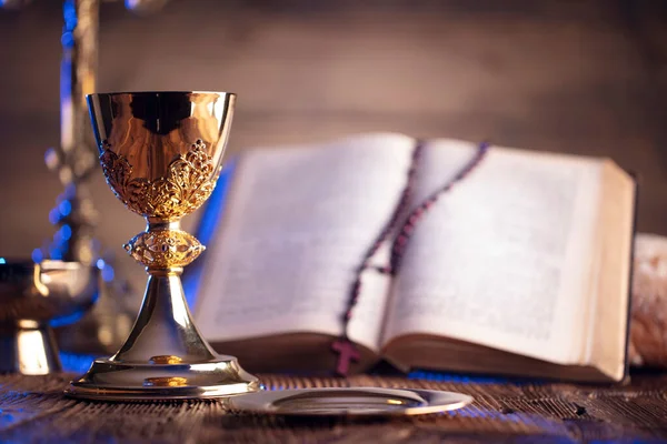 Catholic religion concept. Catholic symbols composition. The Cross, Holy Bible and golden chalice on the altar.