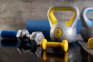 Fitness konsepti. Spor aletleri: ağırlık ölçme makinesi ve dambıl. Gri arkaplan. 