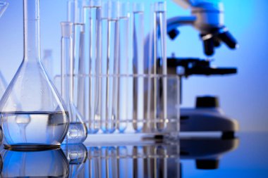 Laboratuvar araştırmaları. Mavi arka planda mikroskop, cam tüpler ve deney tüpleri..