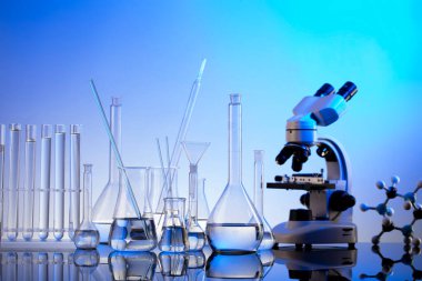 Laboratuvar araştırmaları. Mavi arka planda mikroskop, cam tüpler ve deney tüpleri..