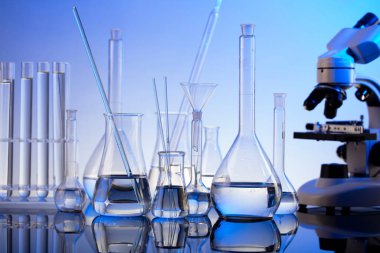 Laboratuvar araştırmaları. Mavi arka planda mikroskop, cam tüpler ve deney tüpleri..