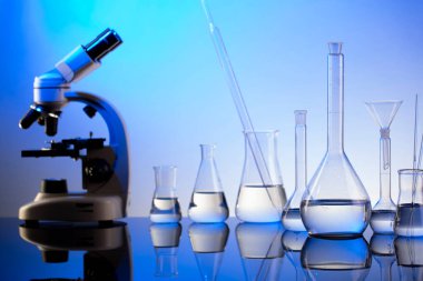 Laboratuvar araştırmaları. Mavi arka planda mikroskop, cam tüpler ve deney tüpleri..