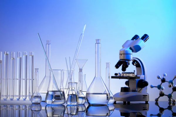 Laboratuvar araştırmaları. Mavi arka planda mikroskop, cam tüpler ve deney tüpleri..