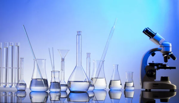 实验室调查 蓝色背景的显微镜 玻璃管和烧杯 — 图库照片
