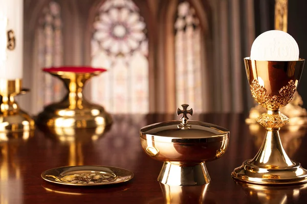 First Holy Communion. Catholic religion theme. Crucifix, the Cross and Golden chalice and wafer on the altar in the church.