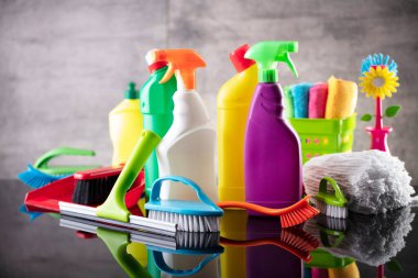 Summer house and office cleaning. Colorful set of bottles with clining liquids and colorful cleaning kit on the gray tiles background.