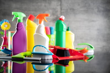 Summer house and office cleaning. Colorful set of bottles with clining liquids and colorful cleaning kit on the gray tiles background.