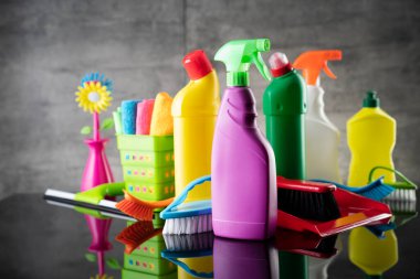 Summer house and office cleaning. Colorful set of bottles with clining liquids and colorful cleaning kit on the gray tiles background.