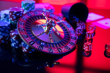 Casino theme.  Roulette wheel, cards, poker chips and dice on red background.