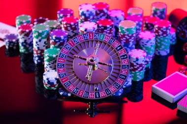 Casino theme.  Roulette wheel, cards, poker chips and dice on red background.