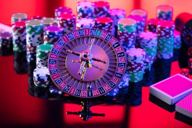 Casino theme.  Roulette wheel, cards, poker chips and dice on red background.