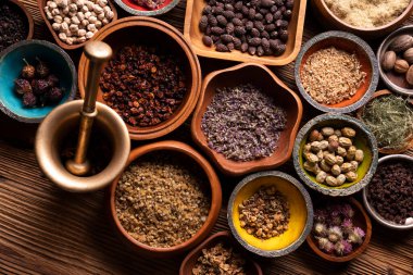 Doğal tıp geçmişi. Kâselerde çeşitli kuru otlar ve rustik ahşap masa üzerinde pirinç havan..