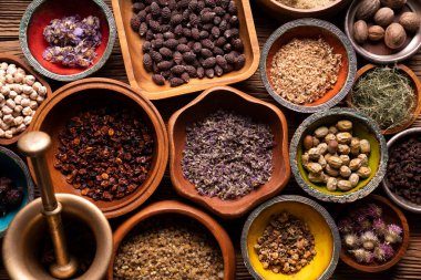 Doğal tıp geçmişi. Kâselerde çeşitli kuru otlar ve rustik ahşap masa üzerinde pirinç havan..