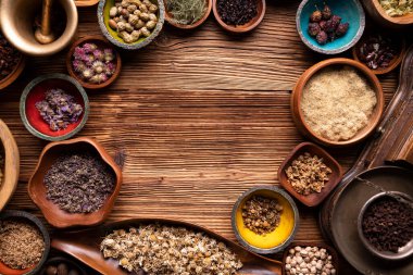 Doğal tıp geçmişi. Kâselerde çeşitli kuru otlar ve rustik ahşap masa üzerinde pirinç havan..