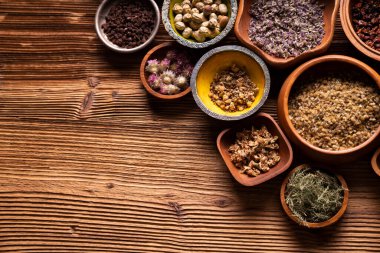 Doğal tıp geçmişi. Kâselerde çeşitli kuru otlar ve rustik ahşap masa üzerinde pirinç havan..