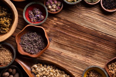 Doğal tıp geçmişi. Kâselerde çeşitli kuru otlar ve rustik ahşap masa üzerinde pirinç havan..