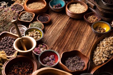 Doğal tıp geçmişi. Kâselerde çeşitli kuru otlar ve rustik ahşap masa üzerinde pirinç havan..