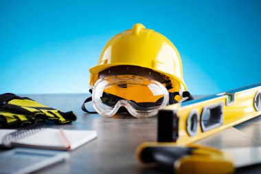 Müteahhit konsepti. Müteahhidin alet çantası: gri fayanslarda sarı baret ve karalamalar ve mavi arka planda.