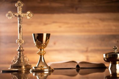 Katolik dini kavramı. Katolik sembolleri kompozisyonu. Haç, Monstrance, Kutsal İncil ve kahverengi arka planda altın kadeh.. 