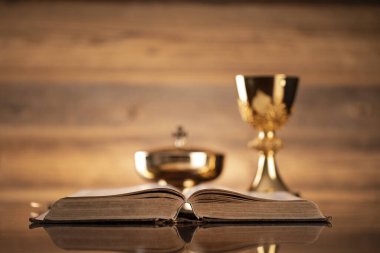 Katolik dini kavramı. Katolik sembolleri kompozisyonu. Haç, Monstrance, Kutsal İncil ve kahverengi arka planda altın kadeh.. 