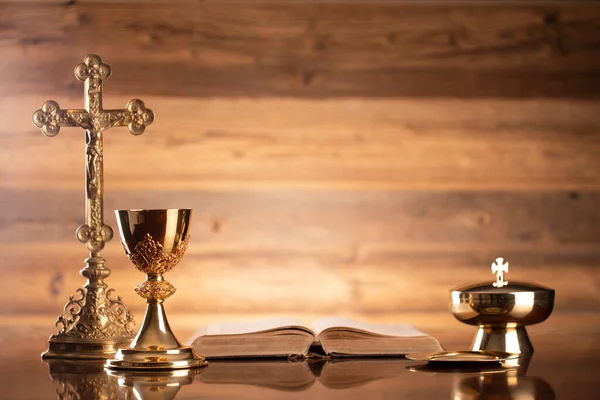 Catholic religion concept. Catholic symbols composition. The Cross, monstrance,  Holy Bible and golden chalice on brown background.