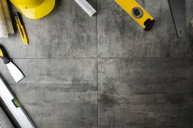 Müteahhit teması. Planlar, müteahhitin alet çantası, sarı başlık ve iftiralar. Gri karolar arka plan.