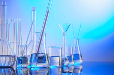 Laboratuvar araştırmaları. Mavi arka planda cam tüpler ve beherler.