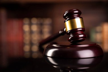 Hukuk teması. Yargıç odası. Gavel kahverengi masada. Kitaplıkta yasal kitap koleksiyonu.