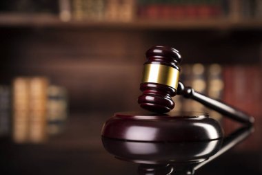 Hukuk teması. Yargıç odası. Gavel kahverengi masada. Kitaplıkta yasal kitap koleksiyonu.