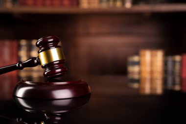 Hukuk teması. Yargıç odası. Gavel kahverengi masada. Kitaplıkta yasal kitap koleksiyonu.