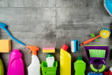 Sonbahar temizliği. Renkli şişeler, yapışkan sıvılar ve gri fayansların üzerindeki renkli temizlik seti..