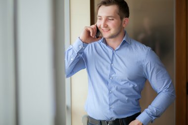 İşadamı parlak ofiste bir telefon görüşmesi görürken 