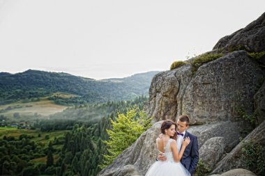Çift ayakta gökyüzüne karşı dağlarda düğün. 