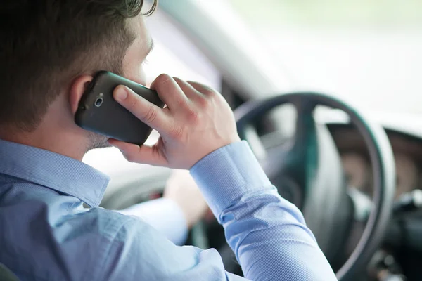 Joven hombre de negocios en su coche al volante hablando en un móvil ph — Foto de Stock