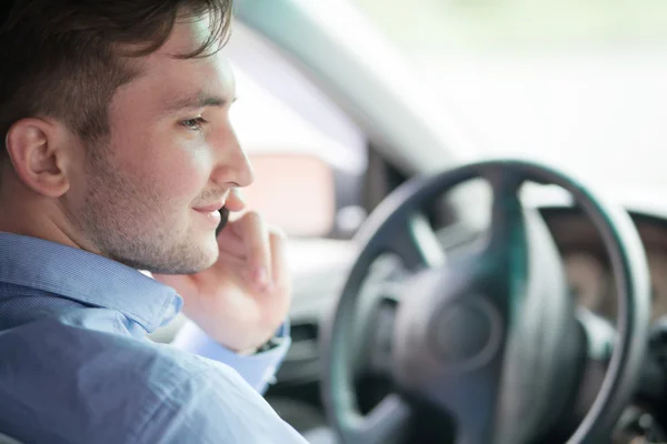 Joven hombre de negocios en su coche al volante hablando en un móvil ph — Foto de Stock