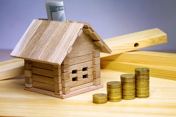 Una pequeña casa de pie en los materiales de construcción y monedas. Crédito f — Foto de Stock