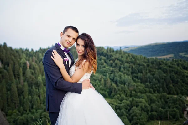 Couple de mariage debout dans les montagnes contre le ciel . — Photo